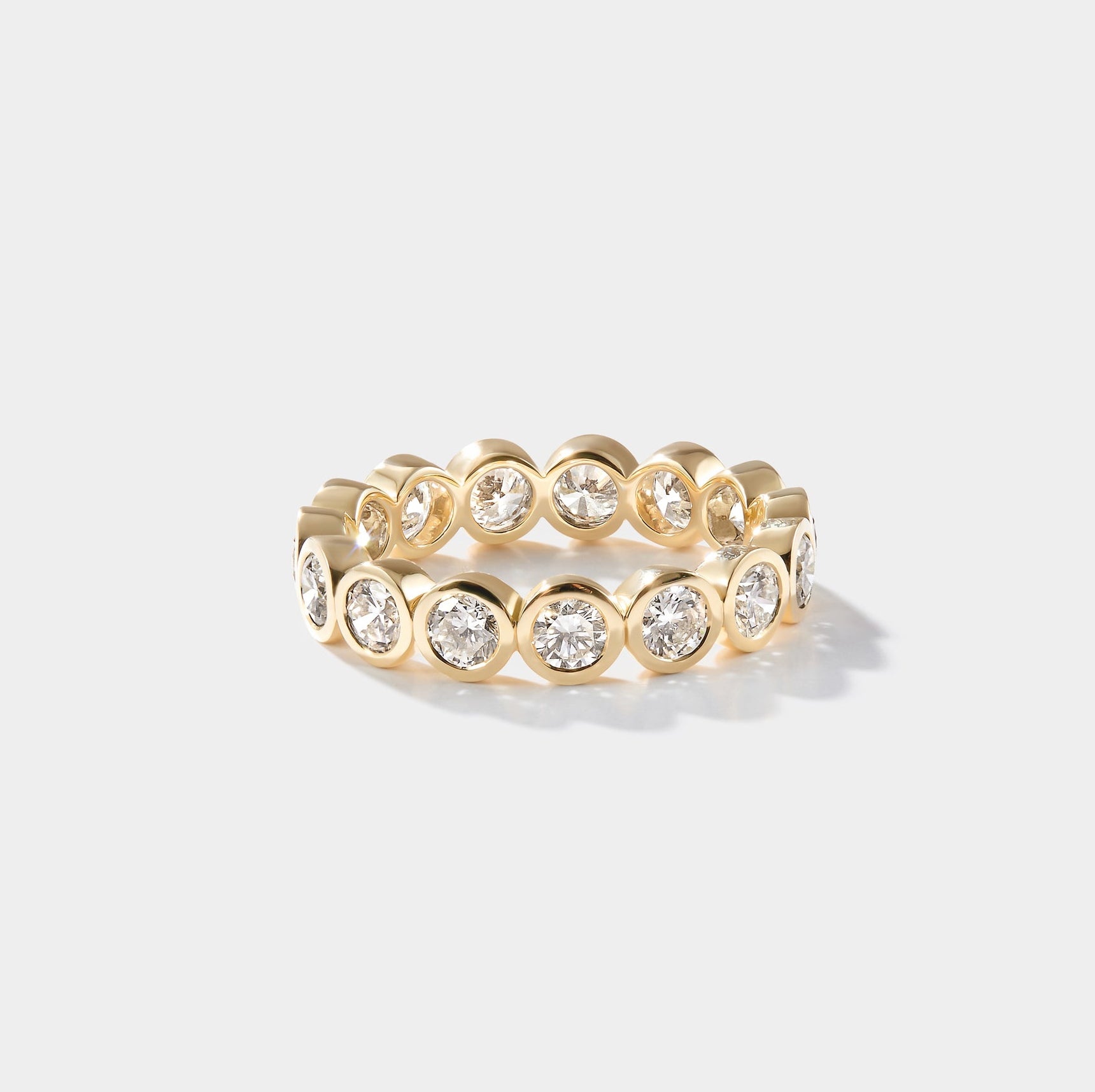 Gold ring with embedded diamonds on a light gray background