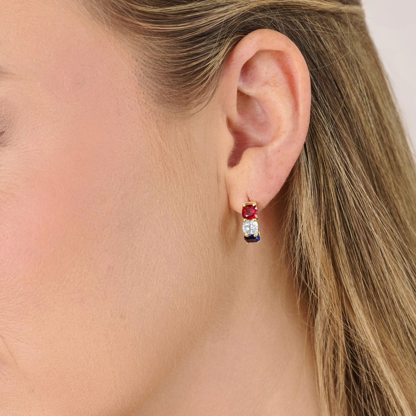 Model wearing America250 cushion cut diamond hoop earrings in solid gold featuring lab-grown diamonds with ruby and sapphire gemstones. Luxury American-made fine jewelry inspired by the United States Semiquincentennial.
