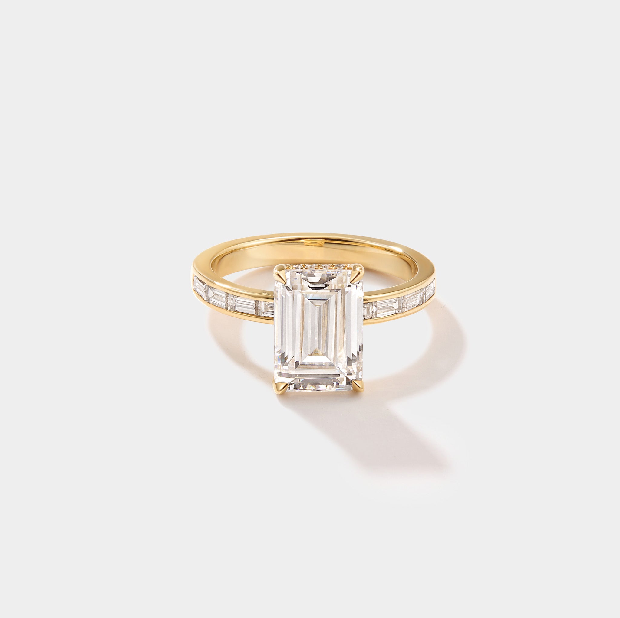 Emerald-cut lab-grown diamond engagement ring with a hidden halo and channel-set band in yellow gold