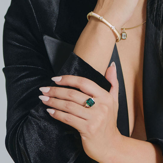 Large emerald cut lab grown emerald ring set in 14k gold worn on model hand