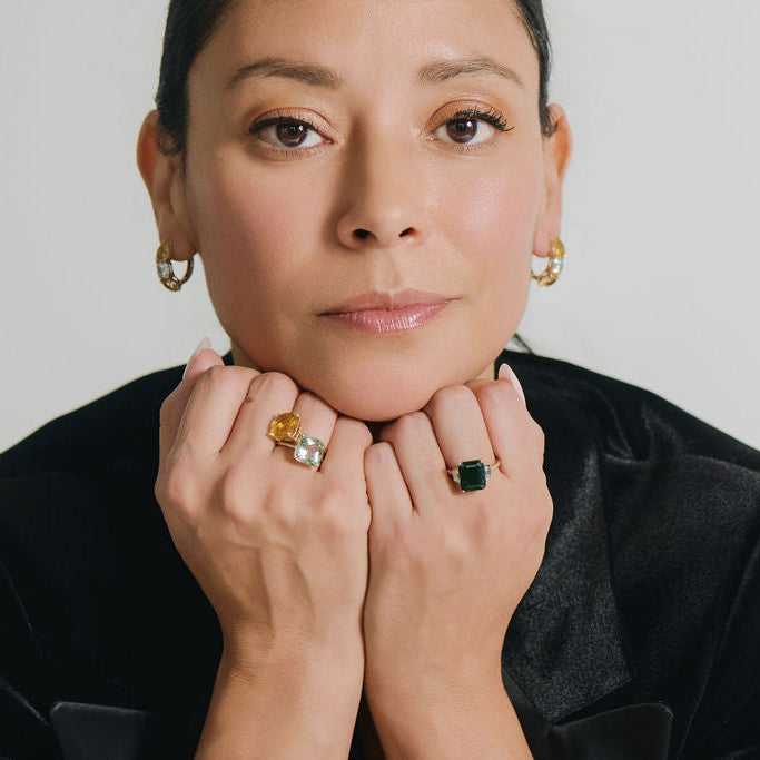 Model wearing lab grown emerald three stone ring with emerald cut emerald and trapezoid diamonds