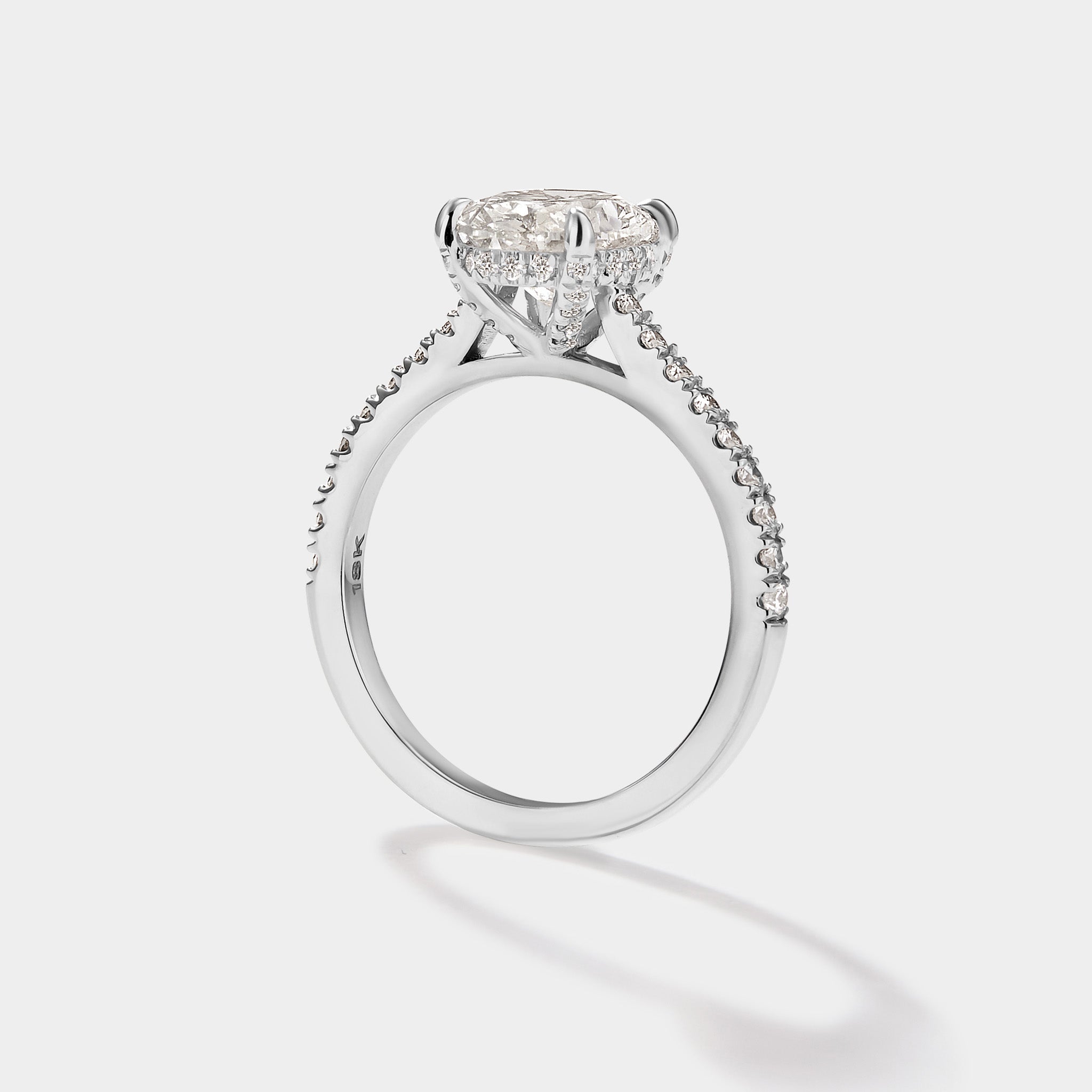 Close-up of oval cathedral halo engagement ring with pave band.