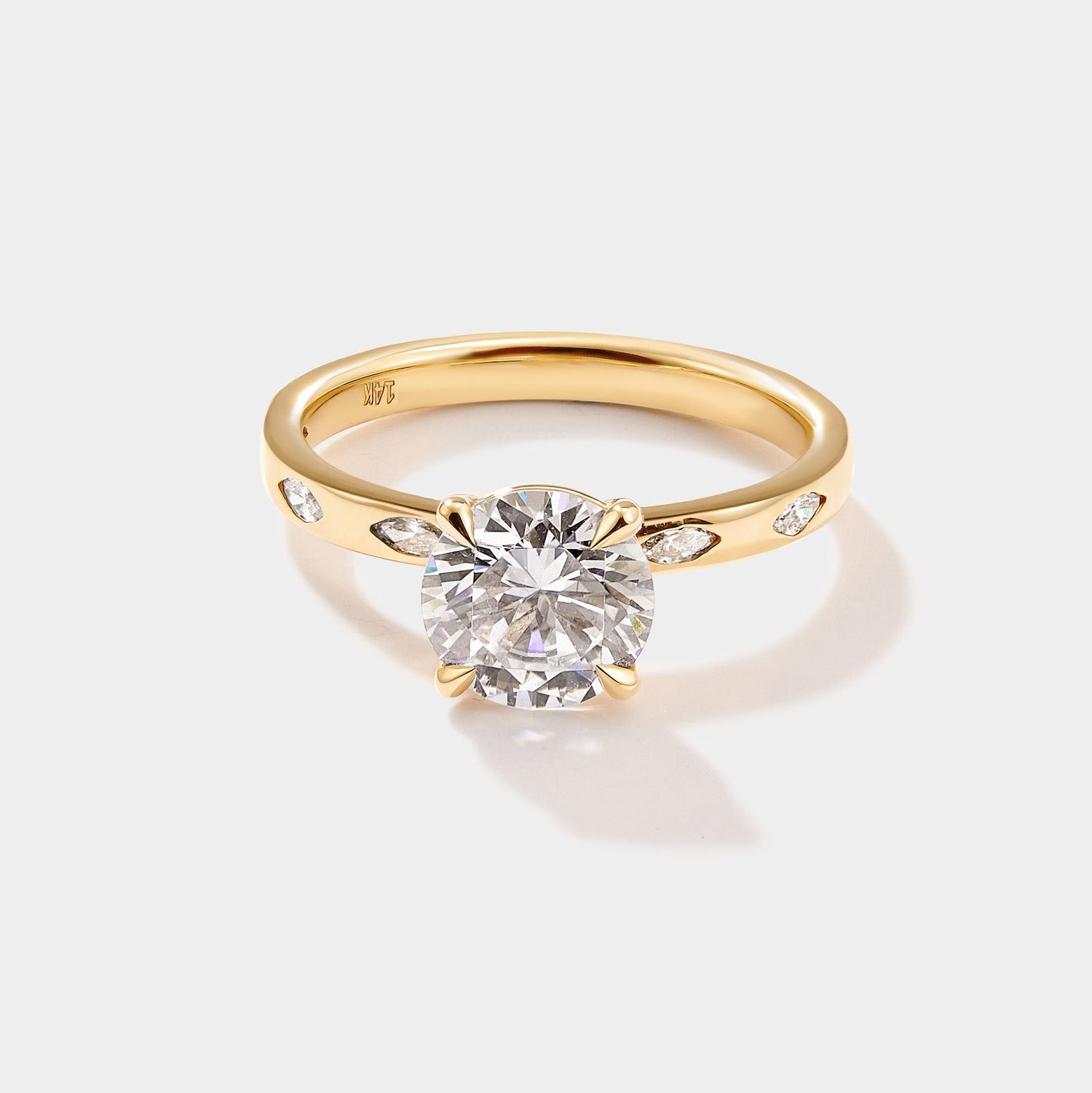 Round solitaire engagement ring with a marquise diamond band in polished gold.