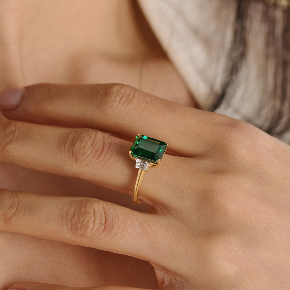 Three stone emerald cut diamond engagement ring with trapezoid side diamonds shown on a model’s hand, handcrafted by Cove Fine Jewelry.