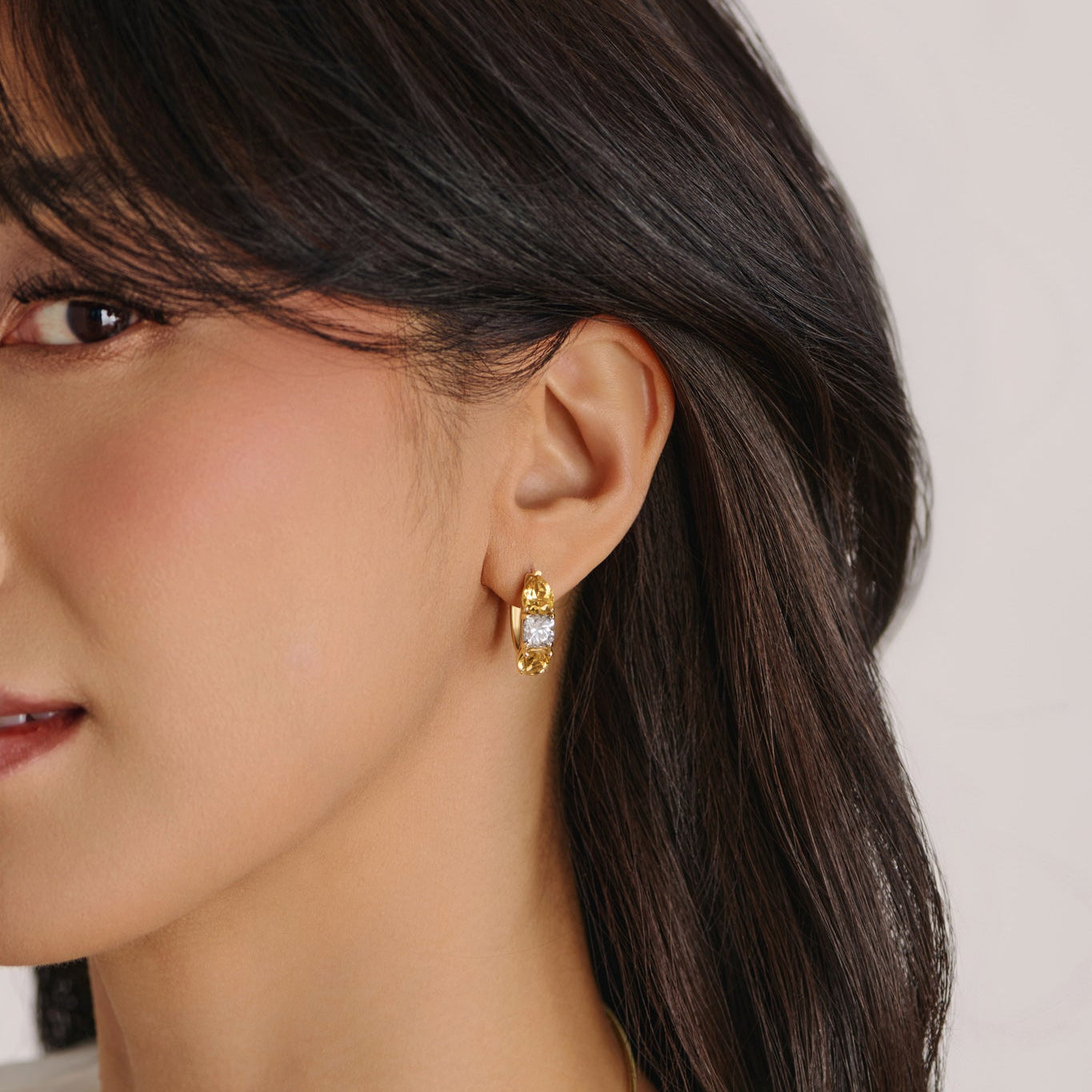 Model wearing 14k gold three-stone hoop earrings with pear and oval citrine and a cushion-cut lab-grown diamond, inspired by Watch Hill Rhode Island coast