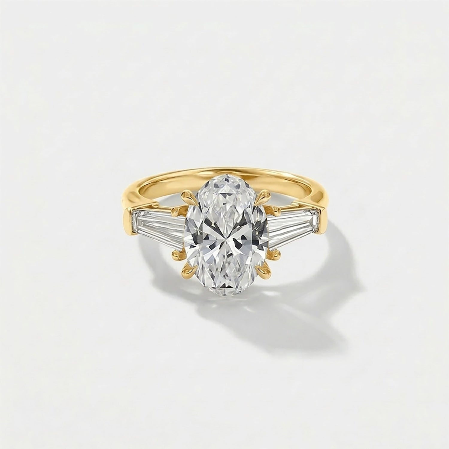 Oval-cut diamond ring with tapered baguette side stones in a classic three-stone setting, elegant and minimalist engagement ring design