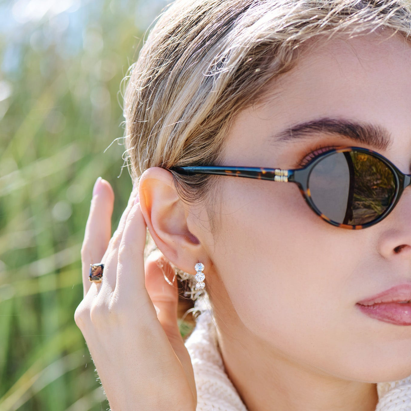 Woman wearing 3 stone round lab grown diamond hoop earrings in solid 14k gold