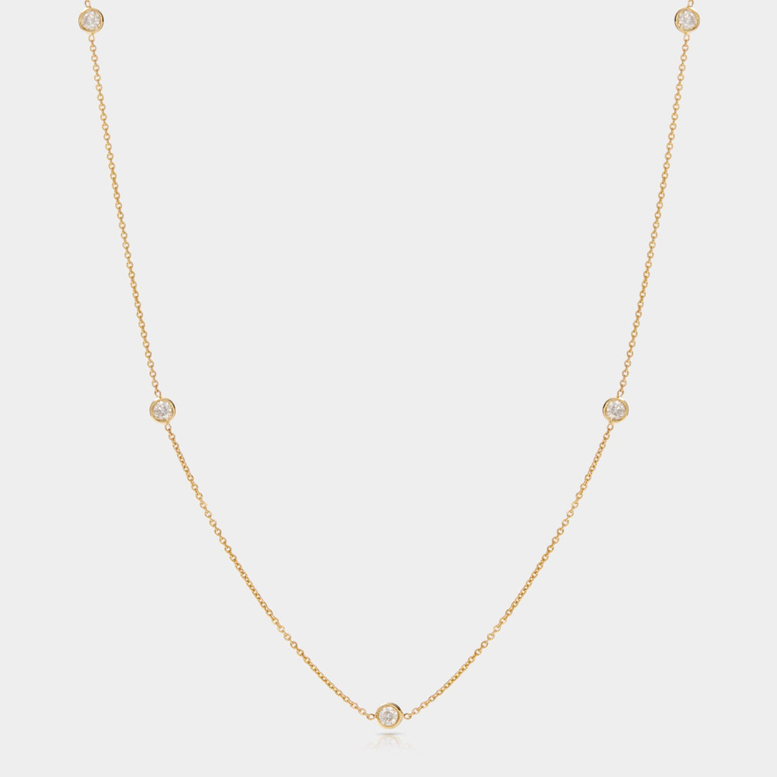 Delicate 18-inch diamond station necklace with five bezel-set diamonds in 14k yellow gold.