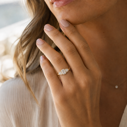 Woman wearing a bezel set ring with side diamonds also bezel set. 