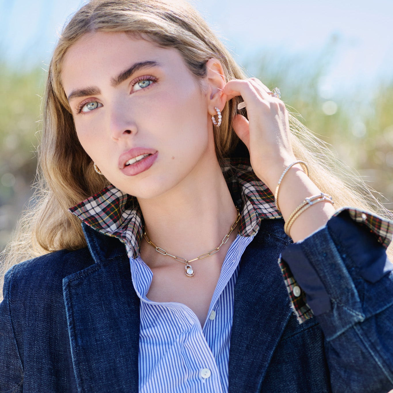 Woman wearing 14k Gold Jewelry on a beach with a gold chain with diamonds on the bail and pendant with lab grown diamonds. 