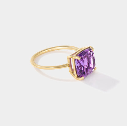 Angled side view of a cushion-cut purple amethyst gemstone ring with four-prong setting and polished yellow gold band.