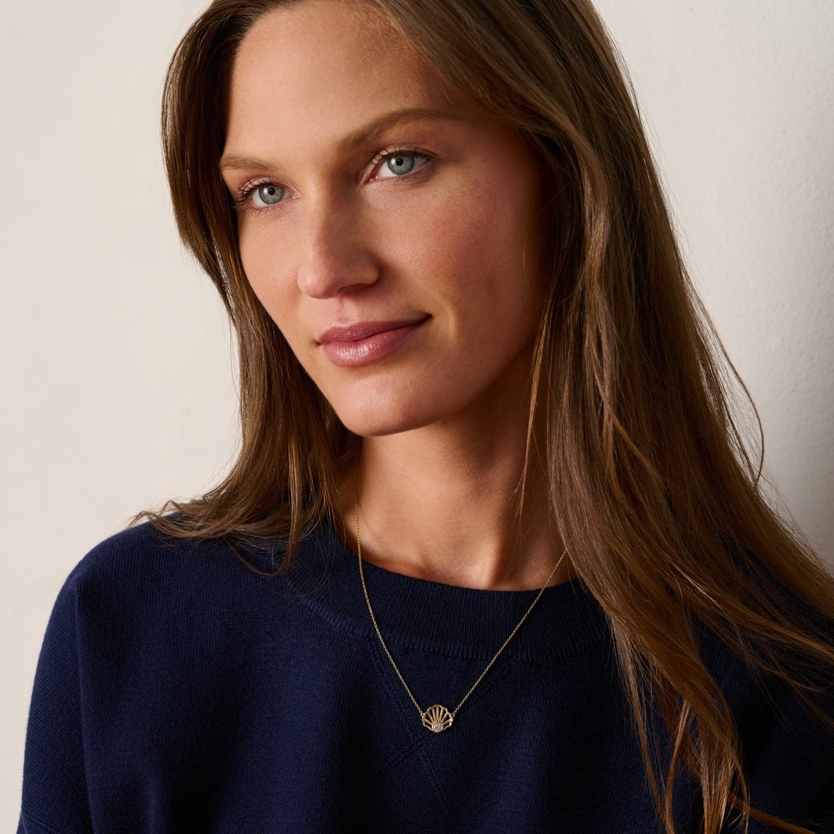 Model wearing a 14K gold scallop shell diamond necklace inspired by the beaches and coastal style of Cape Cod.