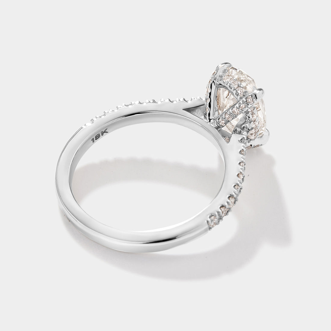 Close-up of oval cathedral halo engagement ring with pave diamonds. 