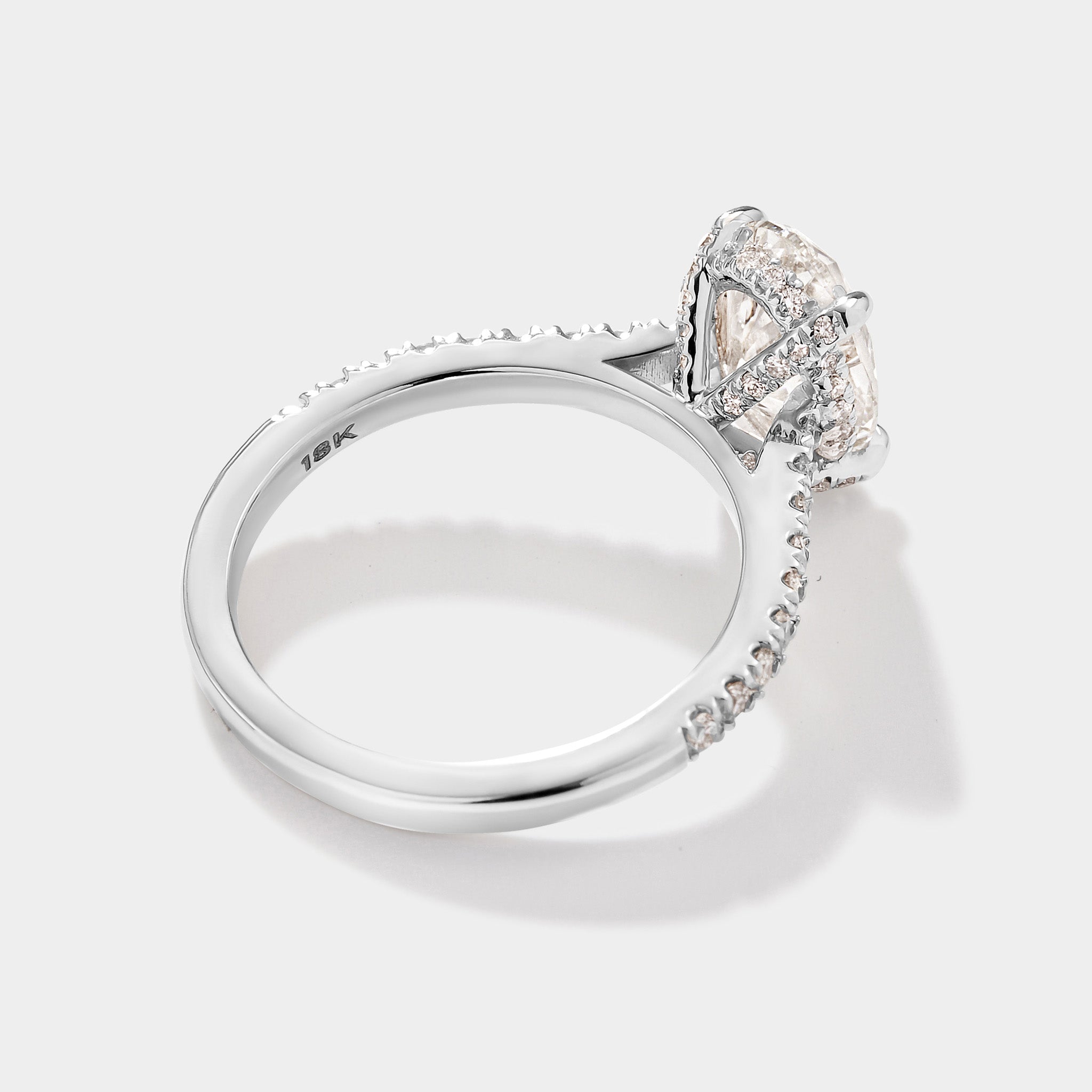 Close-up of oval cathedral halo engagement ring with pave diamonds. 