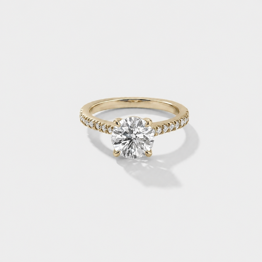Cathedral hidden halo engagement ring with a round diamond center and pavé diamond band in yellow gold.