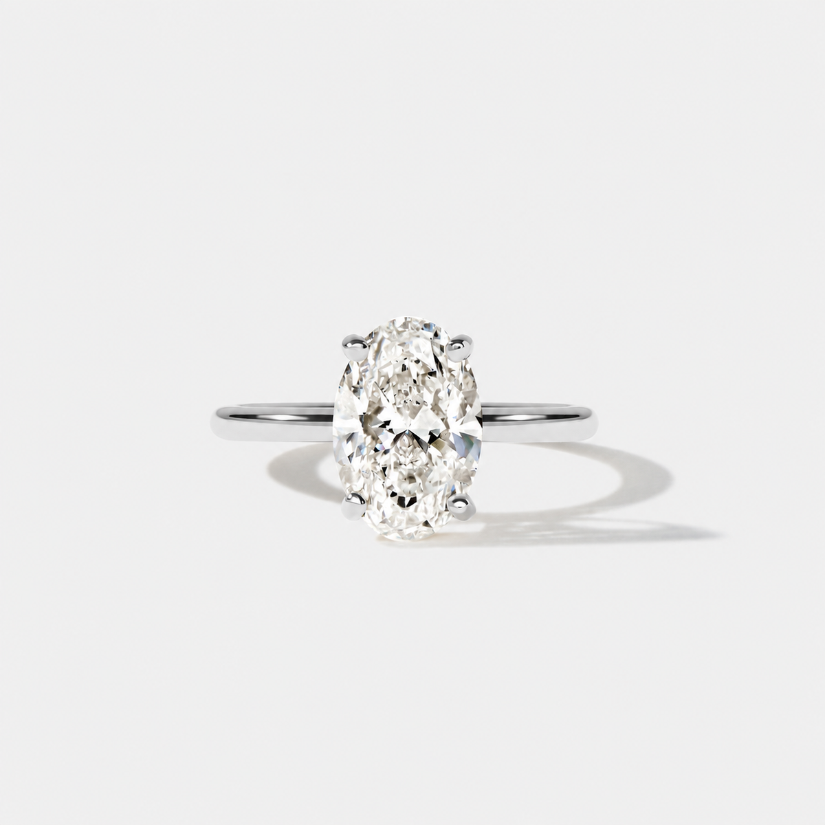 Front view of an elongated oval diamond engagement ring in polished white gold with a classic four-prong solitaire setting.