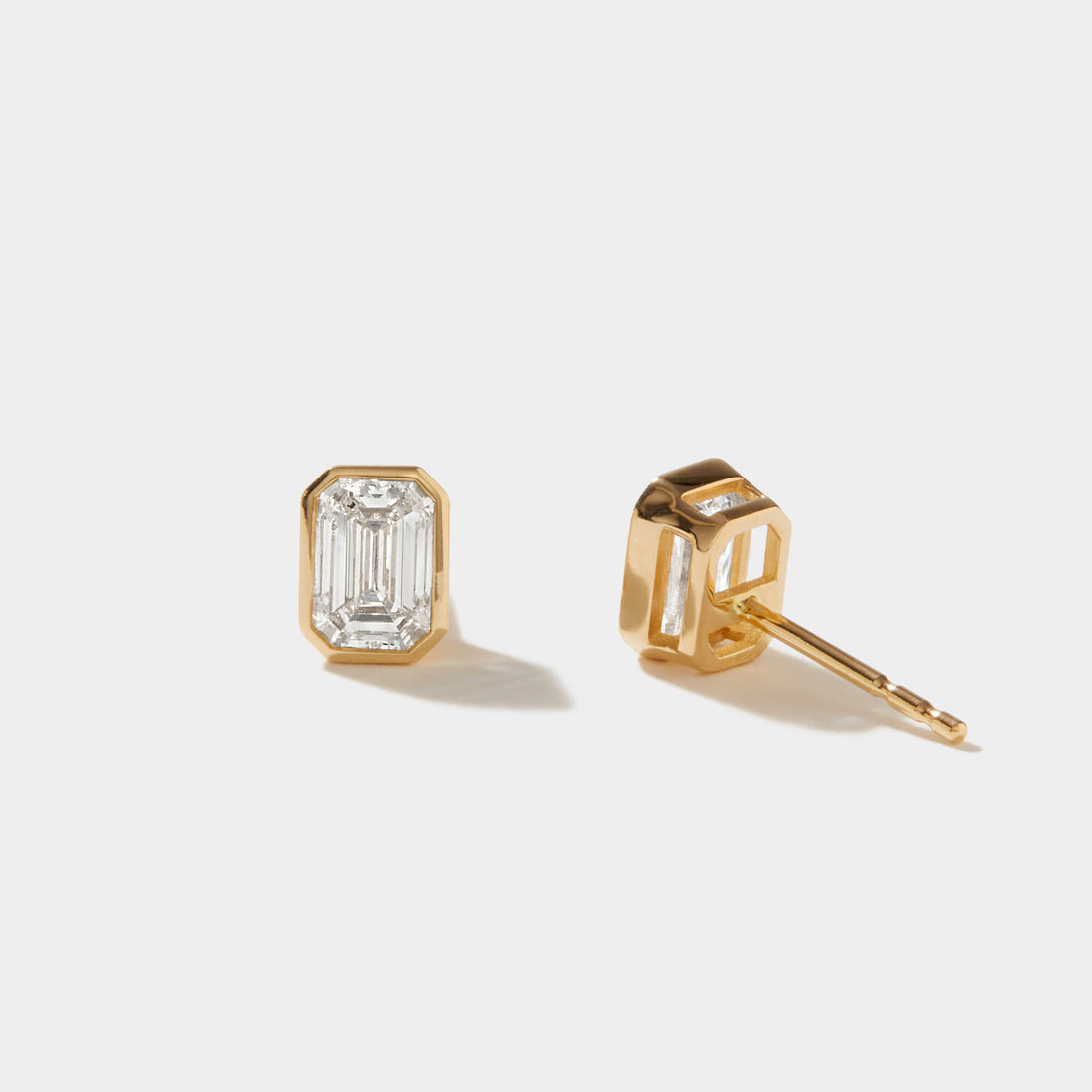 Side view of emerald-cut lab-grown diamond stud earrings in protective 14k gold bezel settings
