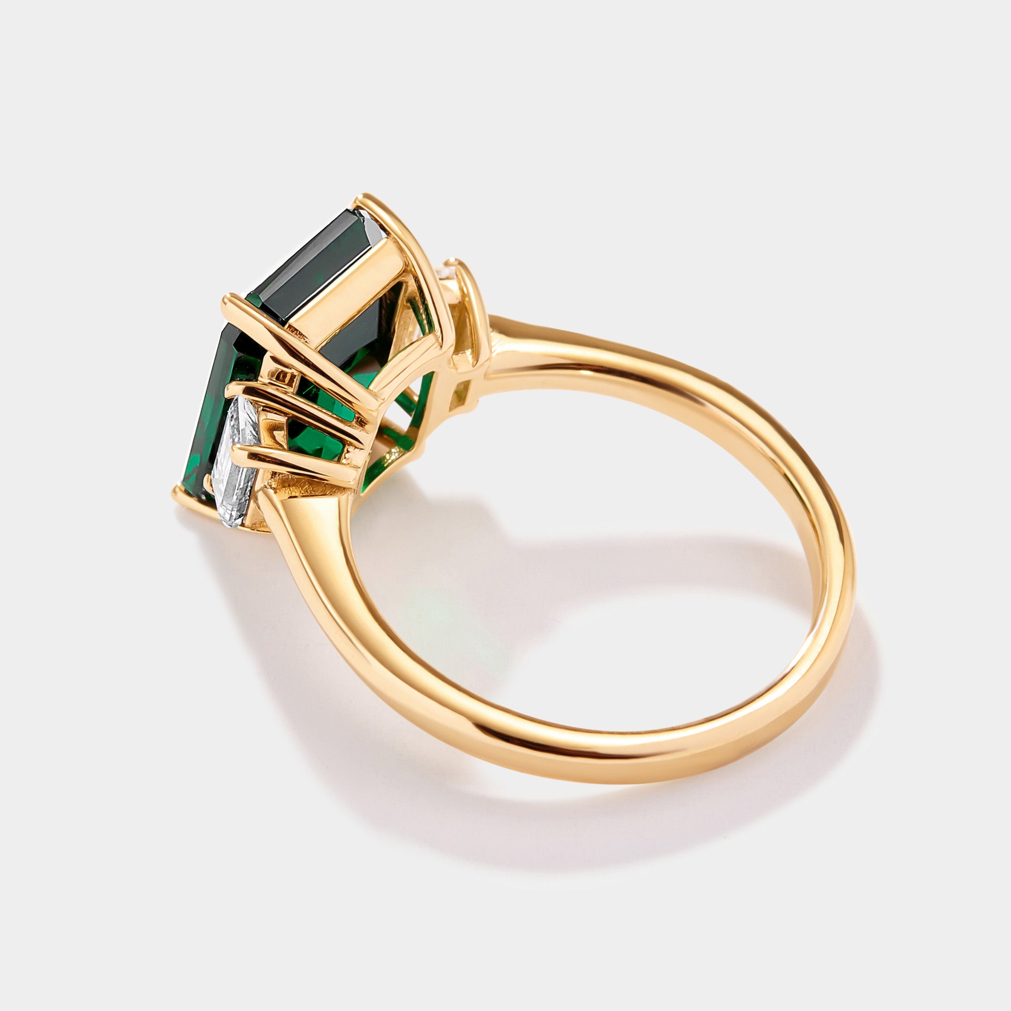 Emerald cut lab grown emerald ring with step cut trapezoid diamond side stones in solid 14k gold