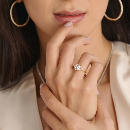 Close-up of emerald cut three stone engagement ring handcrafted by Cove Fine Jewelry