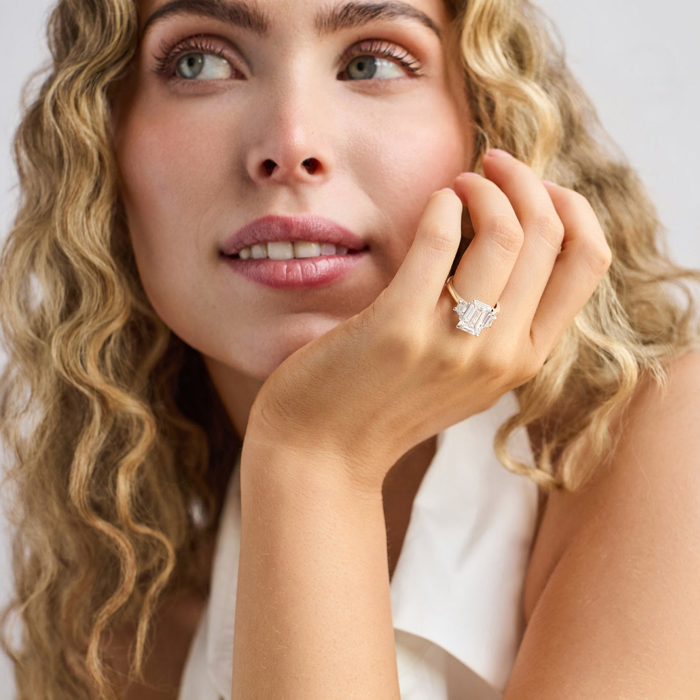 Close-up of emerald cut three stone engagement ring handcrafted by Cove Fine Jewelry