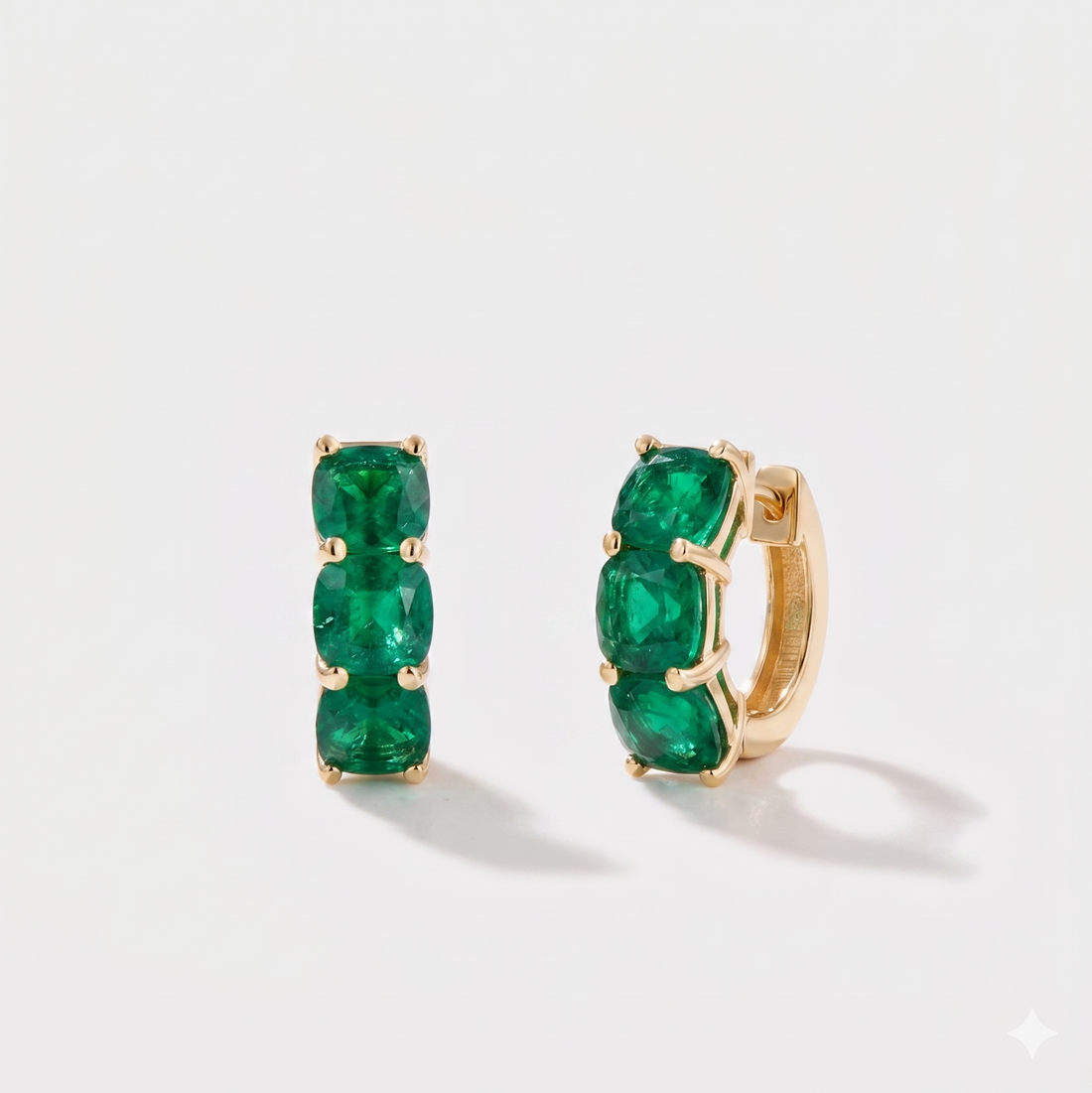 Close-up of cushion cut emerald hoop earrings on ear in 14k gold 