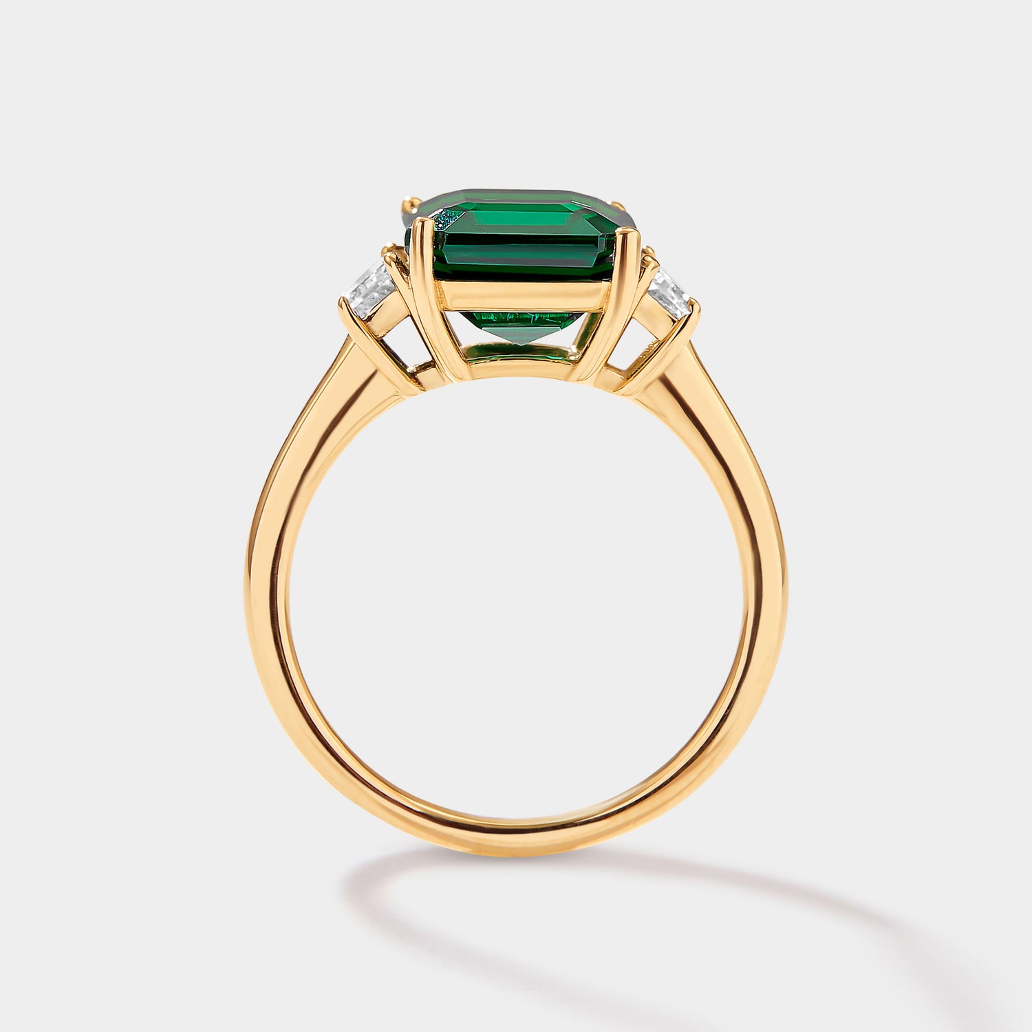 lab grown emerald three stone ring with emerald cut emerald and trapezoid diamonds