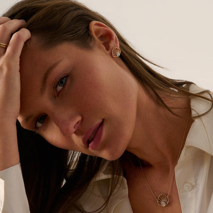 Close-up angle of gold diamond scallop stud earrings paired with a matching scallop necklace by Cove Fine Jewelry.