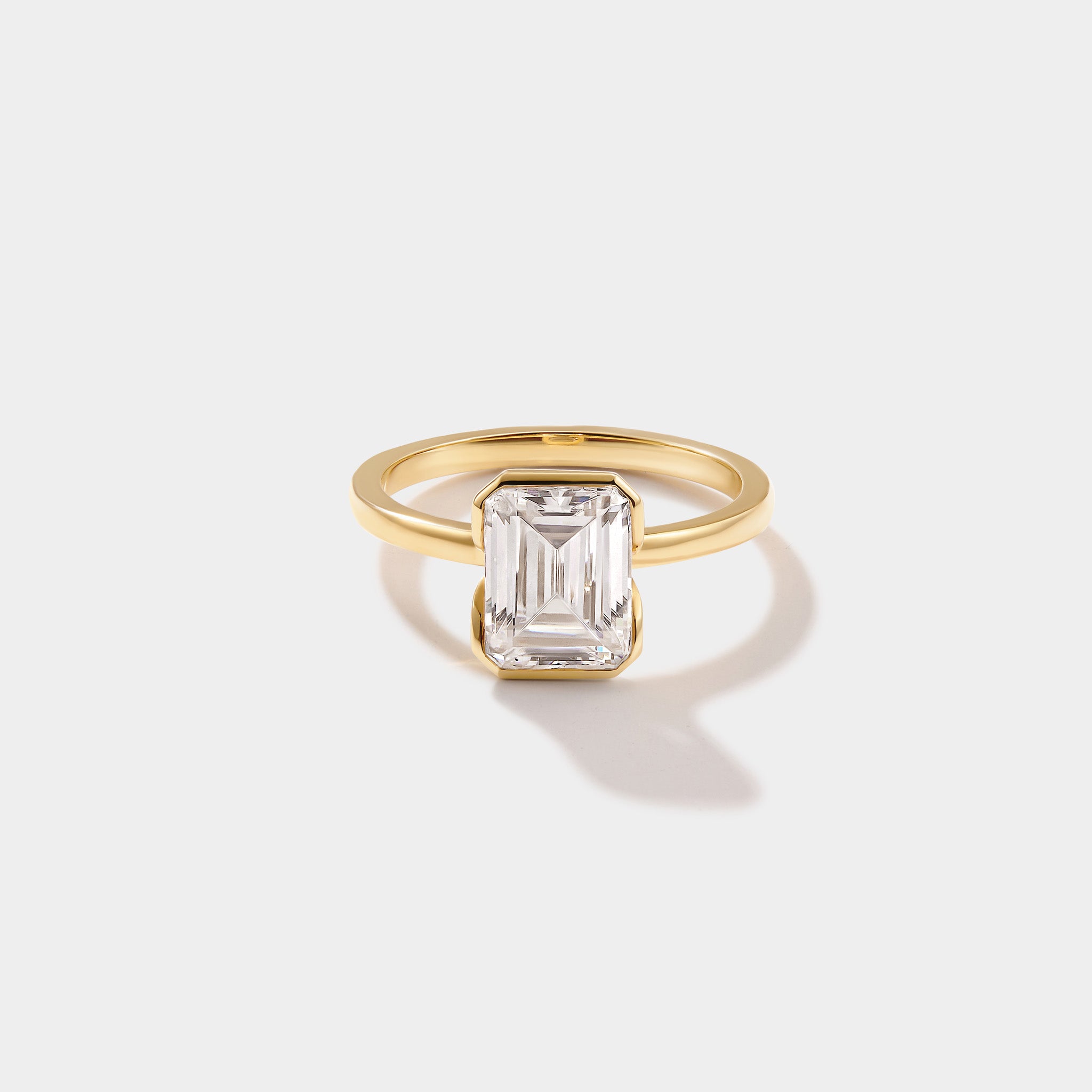 Emerald-cut lab-grown diamond engagement ring in a modern half-bezel solitaire setting by Cove Fine Jewelry.