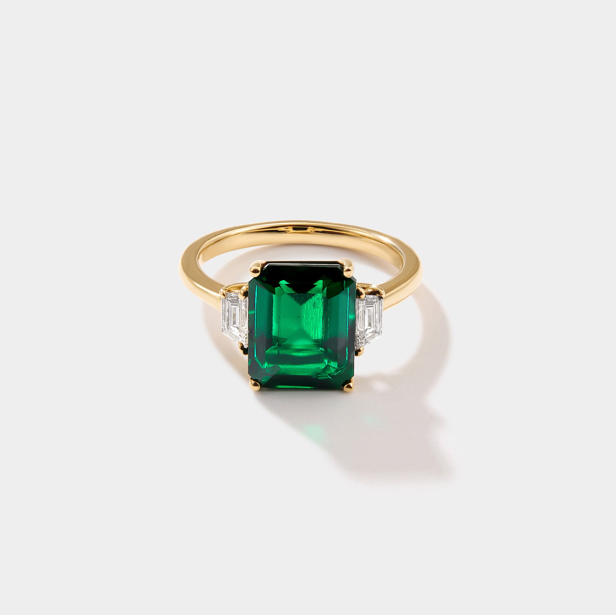 Lab grown emerald three stone ring in 14k gold with emerald cut emerald and trapezoid diamonds