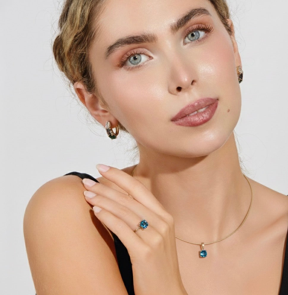 Model wearing London blue topaz pendant necklace with green lab diamond accents in 14k gold by Cove Fine Jewelry.