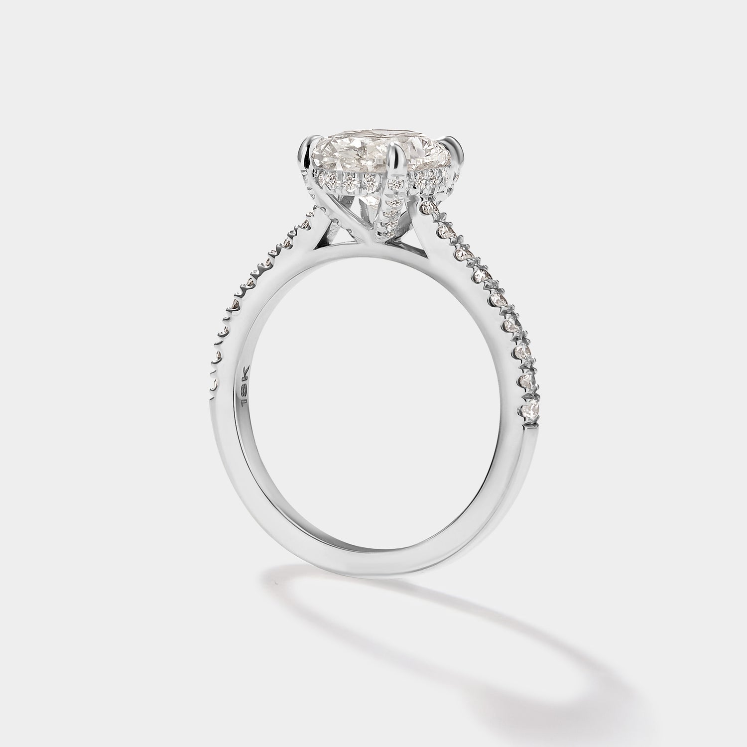 Close-up of oval cathedral halo engagement ring with pave band.