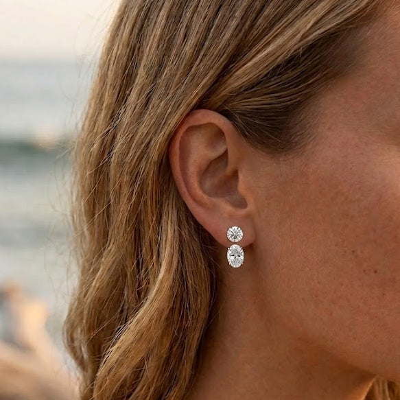 Model wearing oval lab-grown diamond earring jackets below diamond studs