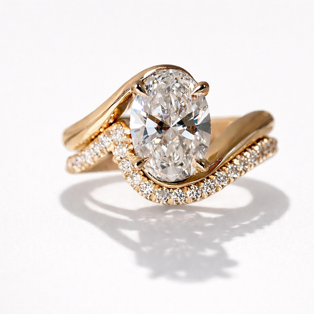 Oval diamond engagement ring in 14k yellow gold with curved pavé diamond band and sculptural wave setting on neutral light background