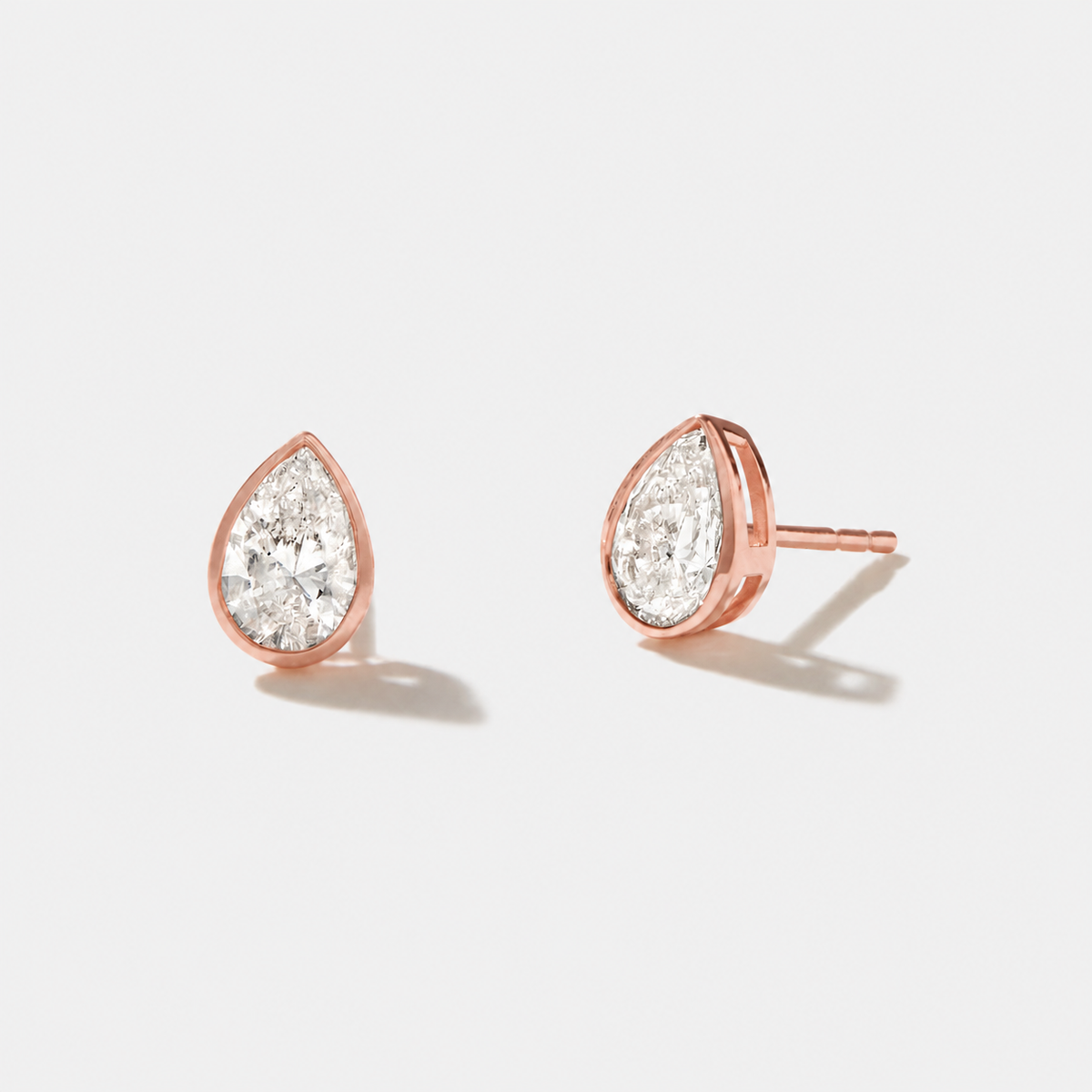 Pear-cut diamond stud earrings in polished rose gold bezel settings