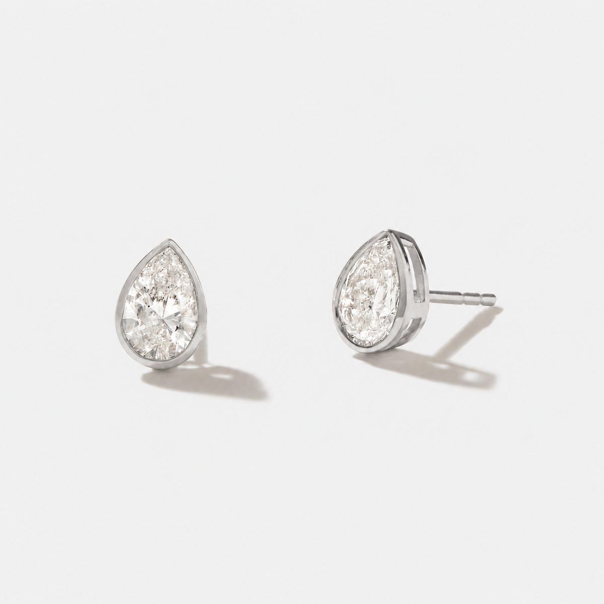 Pear-cut diamond stud earrings in polished white gold bezel settings