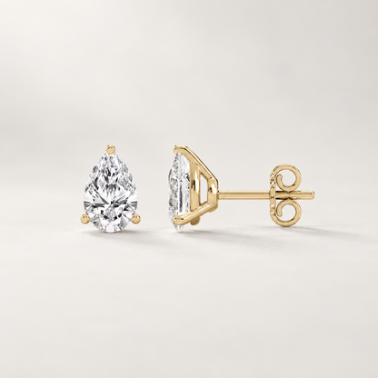 Front and side views of pear-shaped lab-grown diamond stud earrings in yellow gold with three-prong settings.
