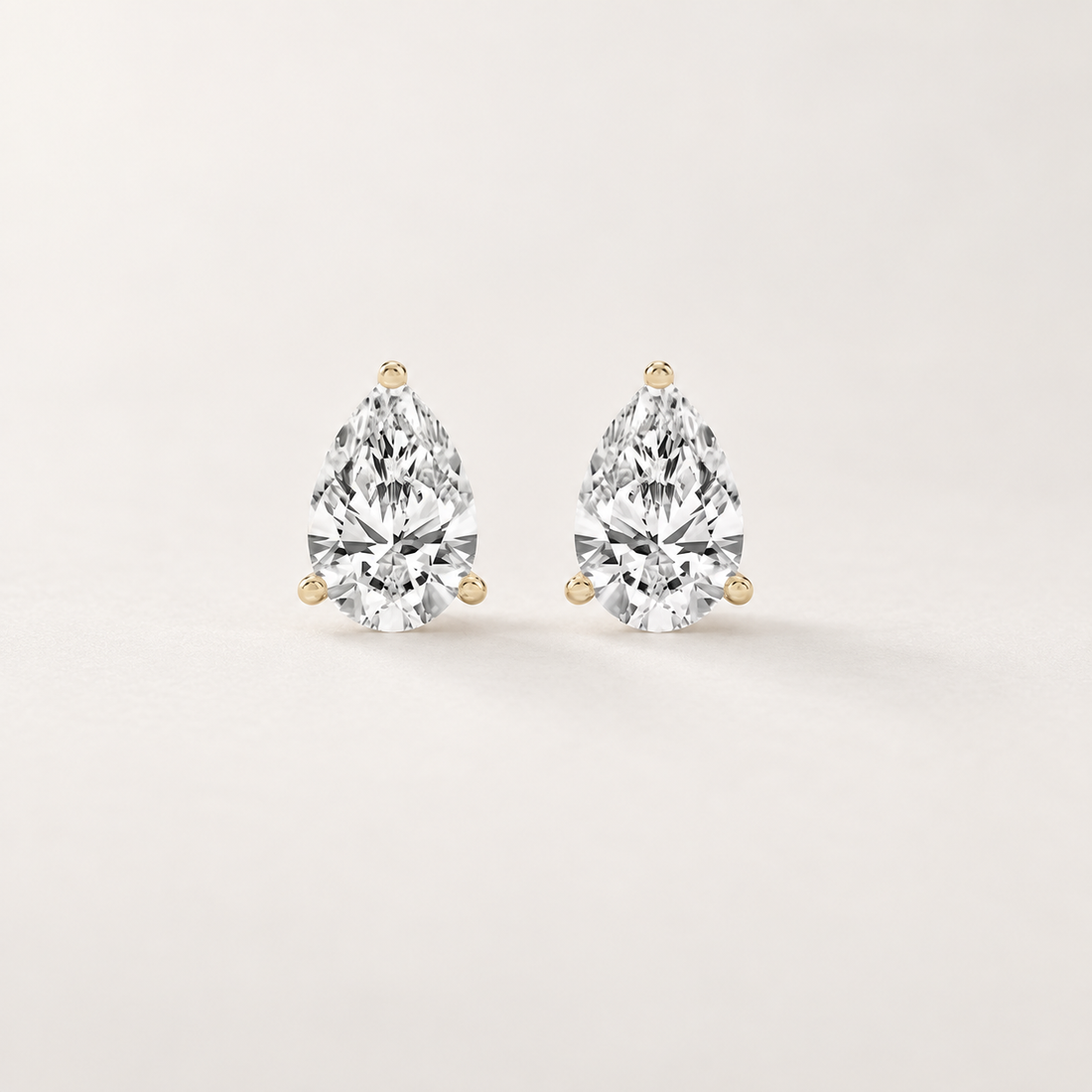 Front and side views of pear-shaped lab-grown diamond stud earrings in yellow gold