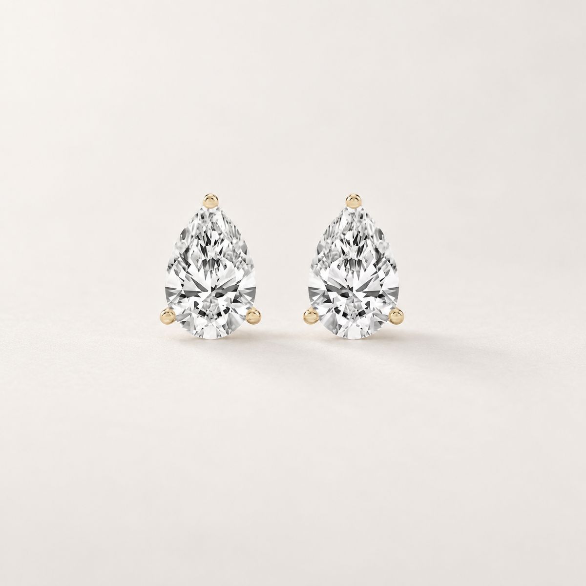 Front and side views of pear-shaped lab-grown diamond stud earrings in yellow gold