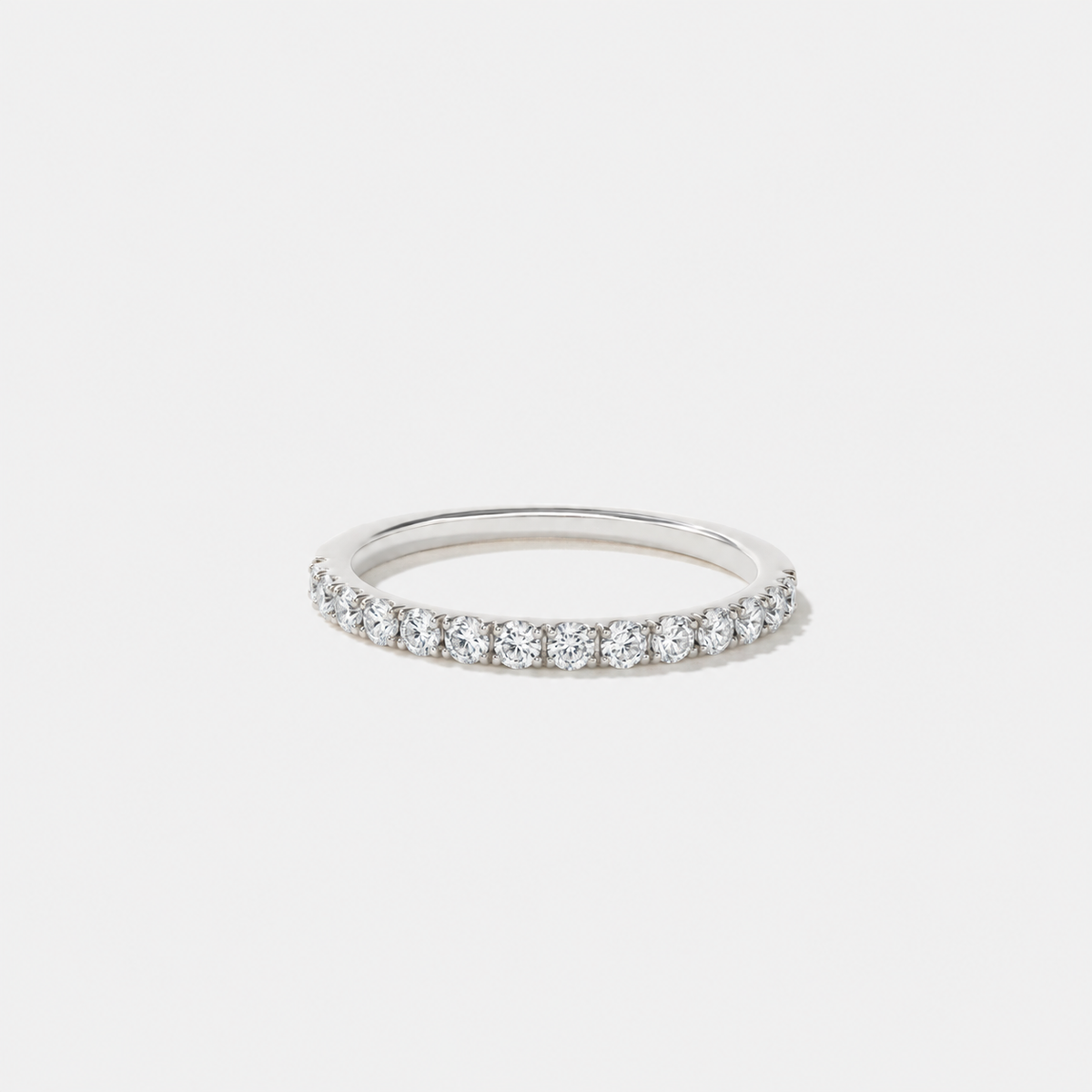 Petite shared-prong wedding band with round lab-grown diamonds set halfway around a slim white gold band.