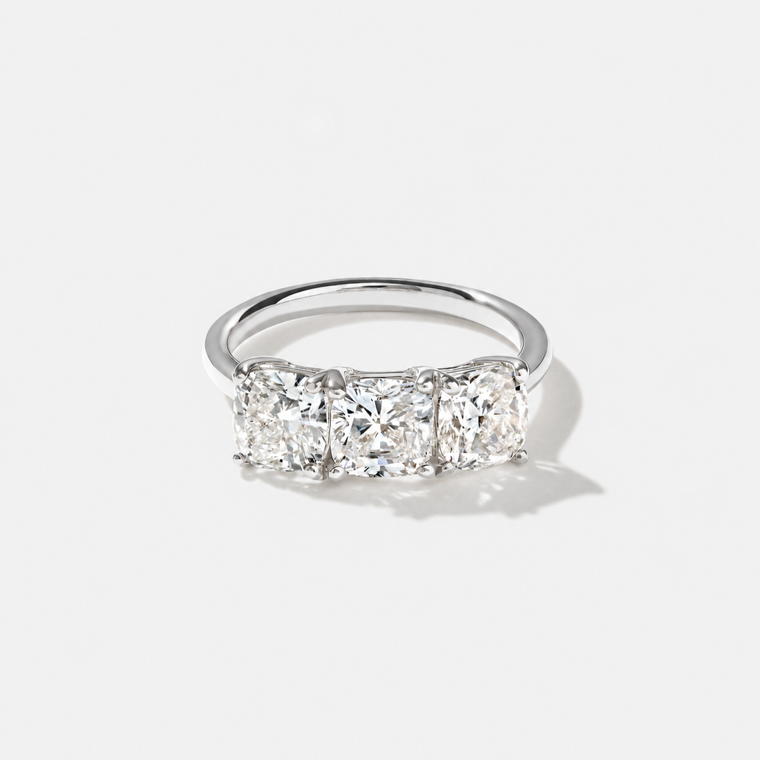Three-stone cushion-cut lab-grown diamond engagement ring in 14K white gold with a larger center diamond and matching side stones.