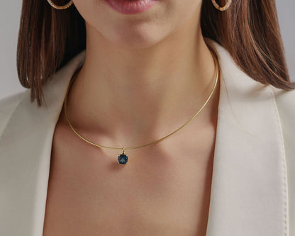 Close-up of a London Blue Topaz pendant necklace on model, featuring a deep ocean-blue gemstone and lab-grown diamond details in solid gold.
